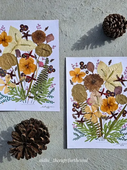 Another view of the two pressed flower arrangements, showing their similarity in composition and color palette.