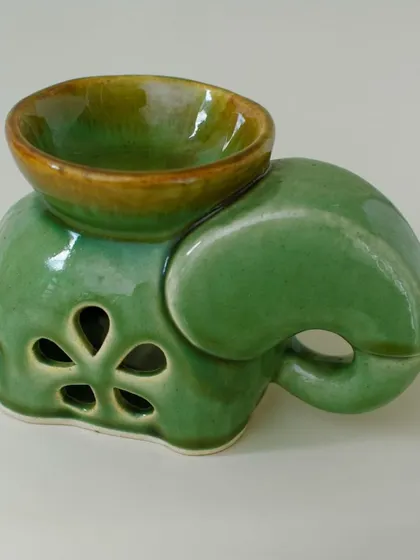 A clean product shot of the elephant oil burner, highlighting its glossy green glaze and the floral-shaped cutouts. It's a charming piece of decor even when not in use.