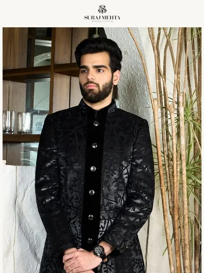 A black-on-black ensemble featuring a patterned sherwani-style jacket with a velvet placket. This look is the definition of nightfall elegance, perfect for a wedding reception.