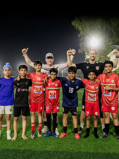 The joy of learning from the best. Our young players pose with coaches from VfB Stuttgart, feeling inspired and motivated after an intense training session. These interactions build confidence and a love for the game.