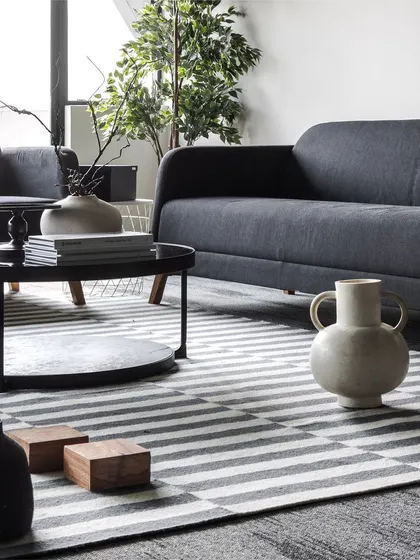 A monochrome waiting area doesn't have to be boring. Here, a striped rug, multi-level coffee table, and curated decor add depth and warmth, creating an inviting first impression.