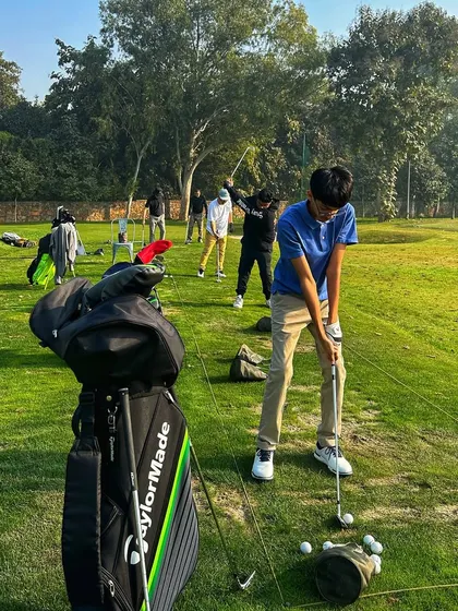 A young golfer stands over his ball, ready to take a shot, with his golf bag in the foreground.