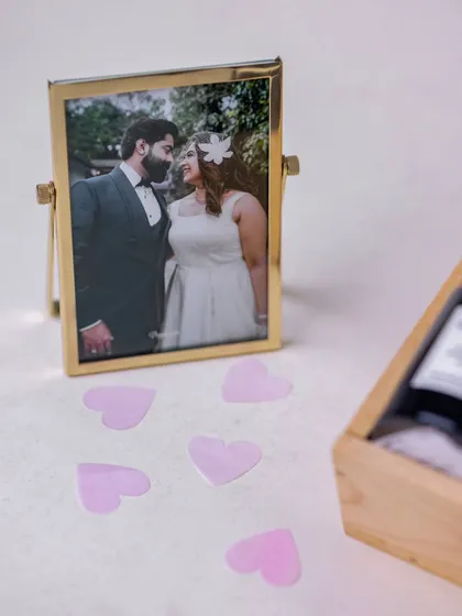 A beautiful brass-finished rotating photo frame with a picture of the couple, included as a timeless keepsake in the newlywed hamper.