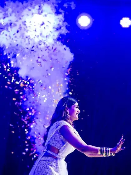 A dramatic shot of the bride's solo performance, highlighted by blue stage lights and smoke effects.
