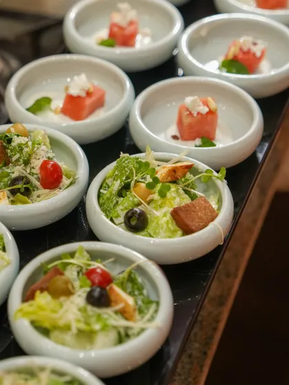 A selection of our mini salads, including a classic Caesar and a refreshing watermelon and feta salad. We offer a wide variety of fresh and elegant salad options in convenient, single-serving portions.