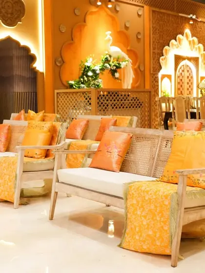 The lounge seating for the Graha Shanti Puja, featuring custom furniture and pure Banarasi hand-woven throws and cushions in shades of orange.