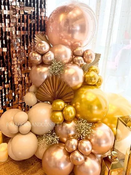 Details that make a difference. This close-up shows the combination of rose gold and gold chrome balloons, with touches of baby's breath and dried palm fans for a boho-glam look.