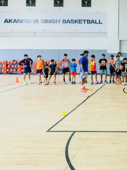 A group of young athletes listen intently to instructions from a coach. Our camps are designed to provide intensive training from professionals in a structured and disciplined environment.