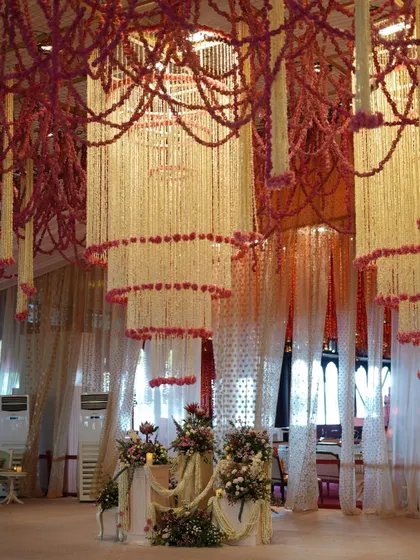 Cascading floral chandeliers made of tuberoses and pink blooms frame the entrance to the wedding ceremony. This design element created a soft, ethereal transition into the main event space.