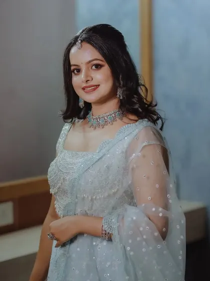 A smiling portrait of a woman in a lovely pastel blue lehenga, ready for an engagement or reception.