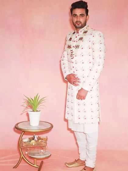 This sherwani features beautiful floral embroidery on the collar and is paired with a simple white kurta. It's a great rental choice for a sophisticated and stylish groom.