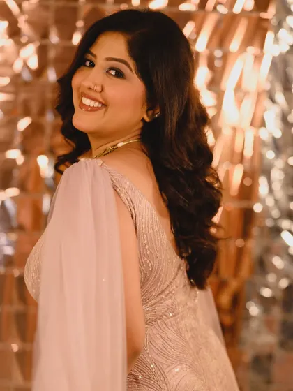 A beautiful smile that lights up the photo. The makeup enhances her natural features and complements the sparkling background.