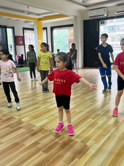 A young dancer in her Trikayaa t-shirt during a kids' fitness and dance class, focused and ready to learn.