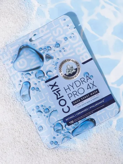A creative product shot of a face sheet mask with printed water droplets on the packaging. I placed it on a sandy surface with a water ripple background to enhance the 'hydra' theme.