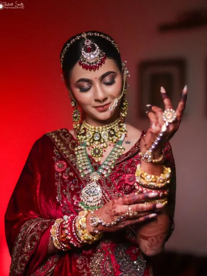 A close-up of the bride admiring her bridal jewelry. This intimate moment, captured under dramatic lighting, emphasizes the intricate details of her look and her quiet anticipation.