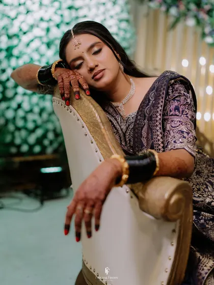 The bride resting her head on the arm of a chair, a moment of quiet elegance amidst the reception festivities.