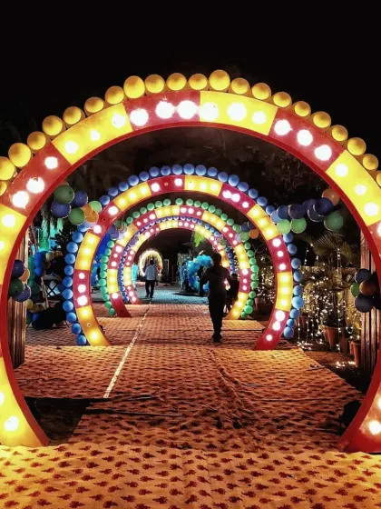 A fun and vibrant entrance for a party or mela-themed event. This setup features a series of colorful, illuminated arches that create a tunnel effect for guests to walk through.