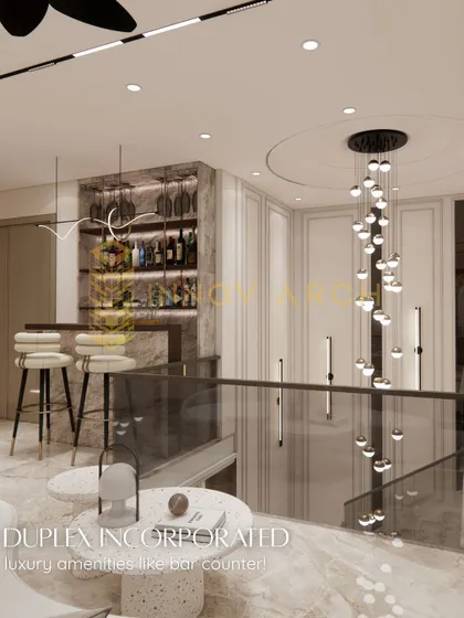 For this duplex, I incorporated a luxurious home bar counter. The design features backlit shelving for bottles, stylish bar stools, and a stunning cascading chandelier over the staircase, creating a perfect spot for entertaining.