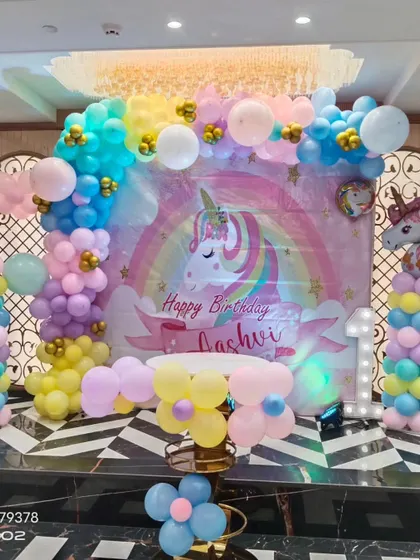 A full view of the unicorn first birthday setup, featuring a large light-up number '1' and a cake table ready for celebration.