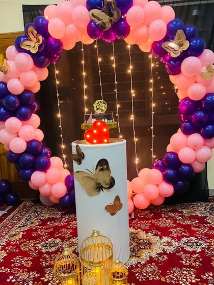 A simple yet beautiful butterfly-themed birthday decor for a home setting. The circular balloon arch is accented with fairy lights for a magical glow.