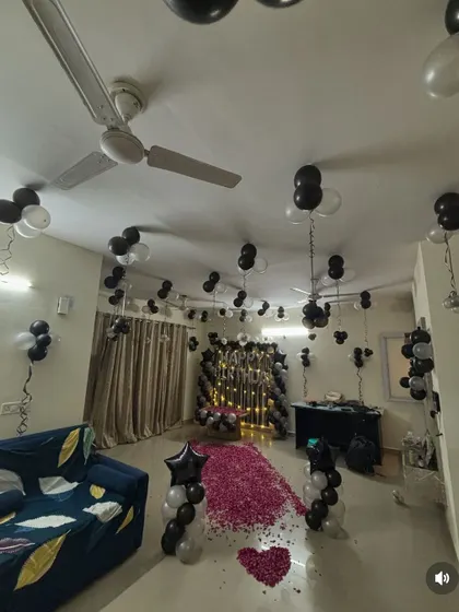 A sophisticated birthday room decoration with a black and white theme, a rose petal pathway, and a decorated backdrop.