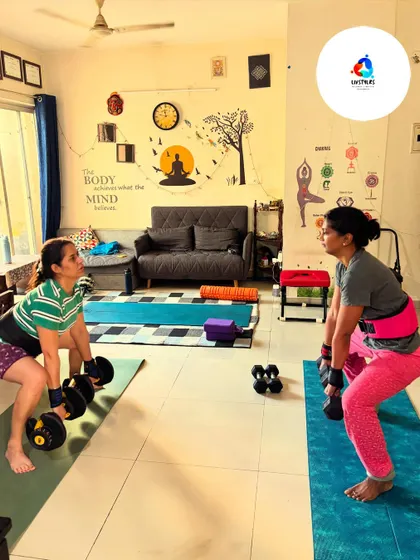 Two clients perform deadlifts, one with adjustable dumbbells and the other with kettlebells. This powerful exercise is key for building posterior chain strength and improving bone density.