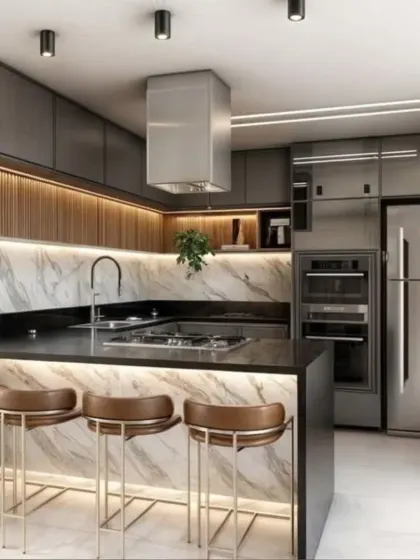 A bold and luxurious kitchen design featuring a marble-clad island with a breakfast counter. The dark cabinets and stainless steel appliances create a sleek, professional look, enhanced by under-counter and backsplash lighting.