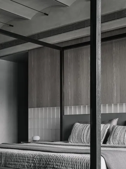 The headboard wall in the Vaulted Haus master bedroom features a combination of frosted glass bricks and grey veneer. The glass bricks can be backlit, transforming the wall into a source of soft, ambient light for the entire room.