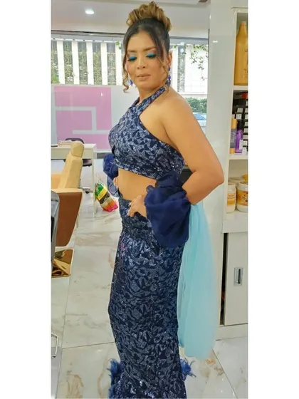 A full-length shot of a client after her party makeover. The makeup is paired with a sophisticated updo, highlighting the halter-neck design of her outfit and creating a chic, cohesive look.
