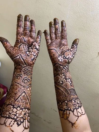 A beautiful example of full coverage bridal mehendi. The design features a mix of floral, paisley, and geometric patterns that create a stunning, intricate sleeve of henna.