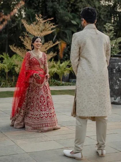 A regal portrait of the couple in their stunning red and cream wedding attire. We use architectural elements like staircases to add a touch of grandeur to our compositions.