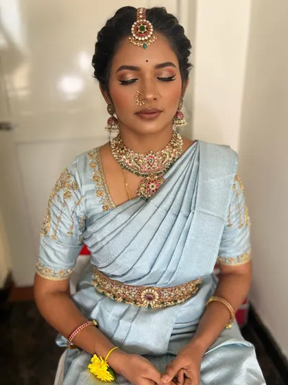 For this client's engagement, we created a soft glam look with a neutral color palette. The focus is on luminous skin, subtly defined eyes, and a nude-brown lip, which looks incredibly elegant with her pastel blue saree.