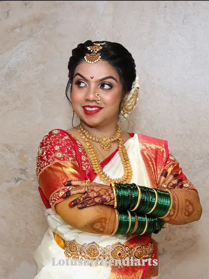 A happy bride with a gorgeous mehendi stain, beautifully accessorized with green bangles and traditional attire.