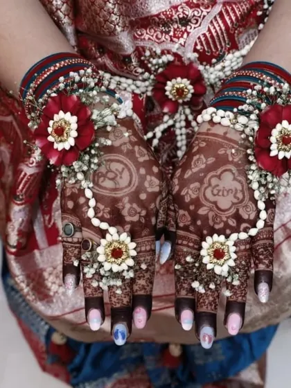 The final look of the baby shower mehndi, beautifully accessorized with floral jewelry. The design includes the names of the parents-to-be.