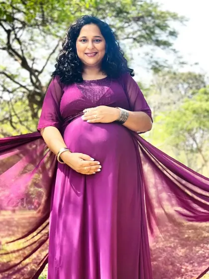 This mom-to-be glows in our deep magenta gown. The dress features a sparkling embellished bodice and sheer sleeves, with a flowing trail that adds a touch of grace to this beautiful outdoor portrait.