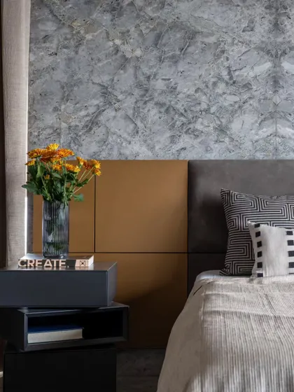 A close-up of the master bedroom's material palette. The cool, veined marble, the warm tan leather, and the crisp linens come together to create a sophisticated and inviting space.
