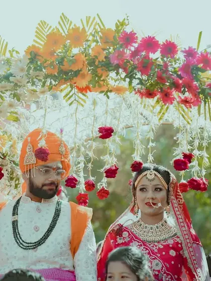 The bride and groom being carried under a beautiful 'phoolon ki chadar' (floral canopy), a classic and beautiful part of a North Indian wedding entry.