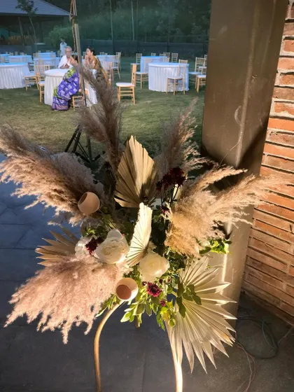 Another angle of the pampas grass arrangement. The soft, feathery texture of the grass contrasts beautifully with the rustic brick wall and the structured palm leaves, creating a visually interesting composition.