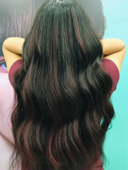 A subtle yet impactful red balayage on long, dark hair. The red tones are painted on to create a gentle gradient, adding warmth and dimension without a full-head commitment.