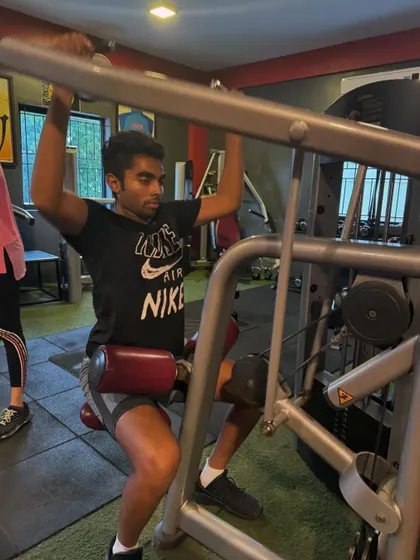 A client uses a lat pulldown machine to strengthen his back muscles. We incorporate both free weights and machines for a well-rounded strength program.
