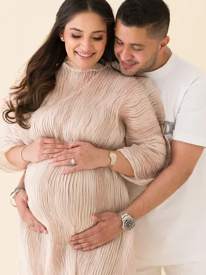 A tender moment captured between an expecting couple. Their gentle touch and soft smiles tell a story of shared love and excitement.