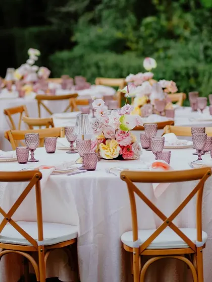 A view of the guest tables, with rustic cross-back chairs and beautiful floral centerpieces.