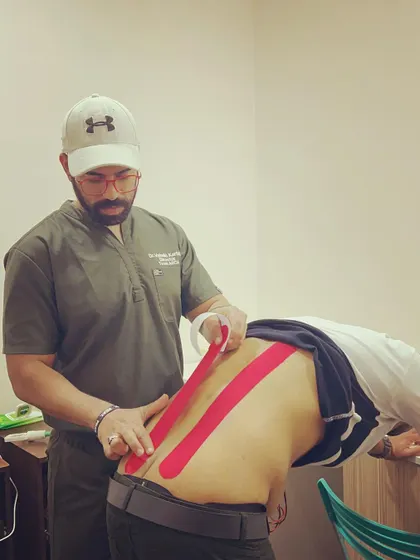 I am applying kinesio tape to a client's lower back. This elastic tape provides support and stability to muscles and joints without restricting range of motion, making it ideal for pain relief during travel or activity.