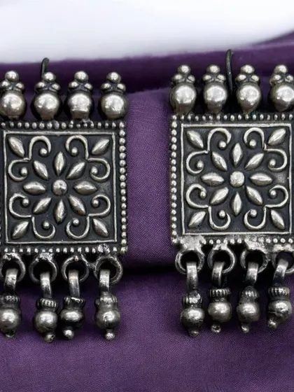 Another pair of elegant, rectangular oxidised silver earrings. These have a beautiful floral-stamped pattern and ghungroo drops.