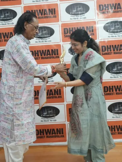 A senior guru presents an award to an adult vocal student, showing our commitment to lifelong learning.