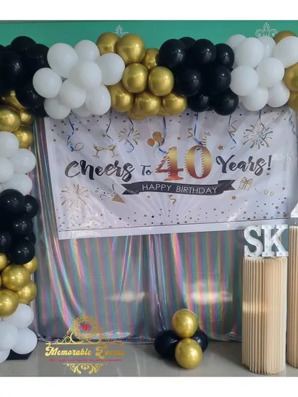 A 'Cheers to 40 Years' milestone birthday setup with a custom banner and a black, white, and gold balloon frame.