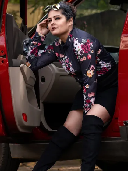 Another shot from the car series, showing the full floral-print top and black mini-skirt. This is a perfect example of modern, confident styling.