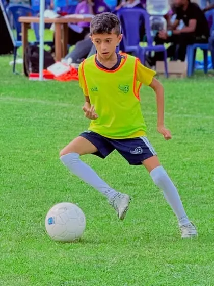 A player dribbling with speed and control during a competitive match. We train our players to be confident on the ball under pressure.
