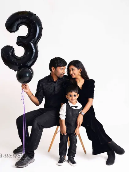 A chic and modern family portrait for a third birthday. The all-black outfits and the simple white background create a sophisticated and timeless look.