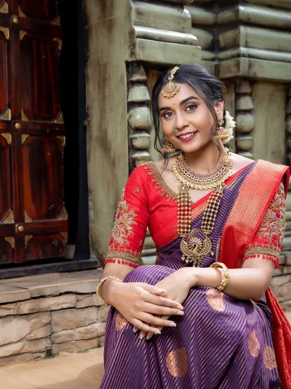 A candid, happy moment captured in a purple and red silk saree. This outfit is perfect for a bride who wants to feel comfortable and elegant throughout her wedding day.